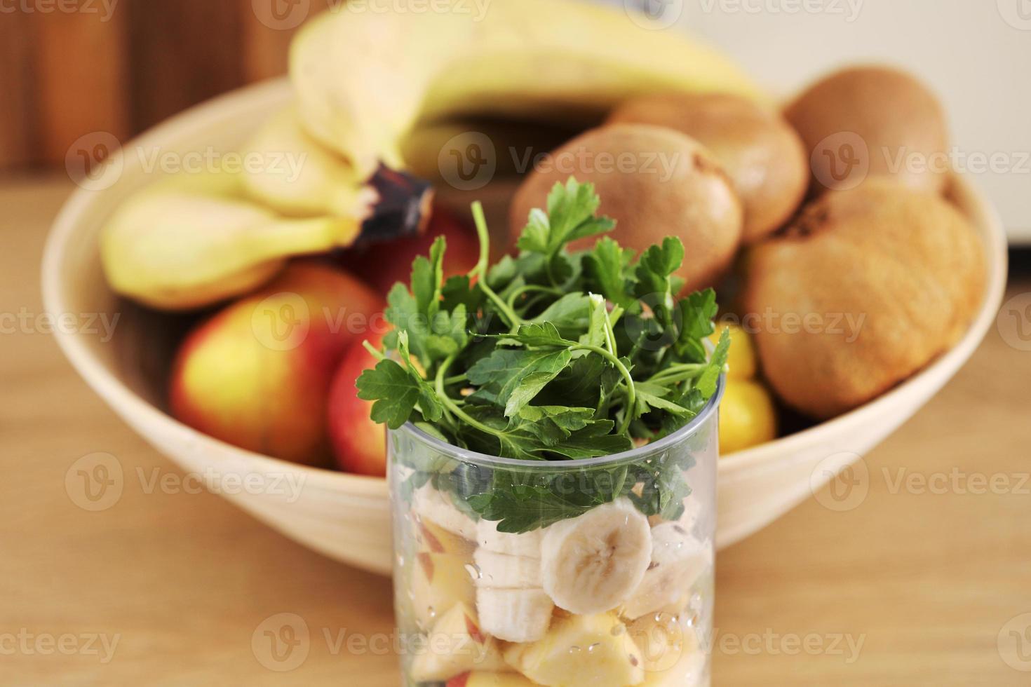 Glas leckerer Joghurt mit Minze und frischen Erdbeeren, Banane, Limette, Nektarine in einem Weidenkorb auf einem Holztisch foto