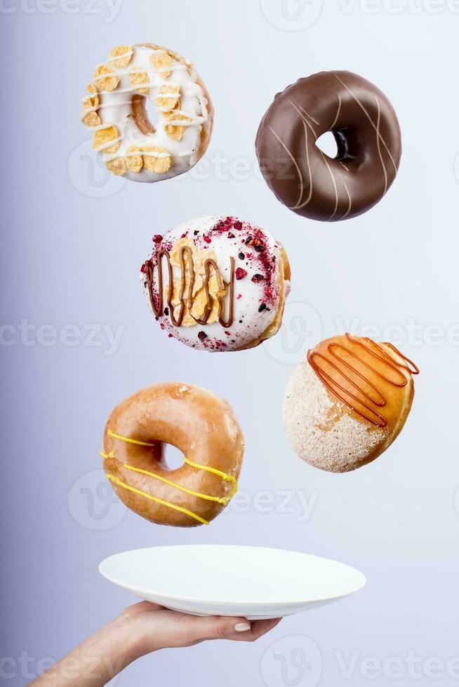 lecker fliegend Donuts mischen von Aromen - - weiblich Hände halten ein Teller foto