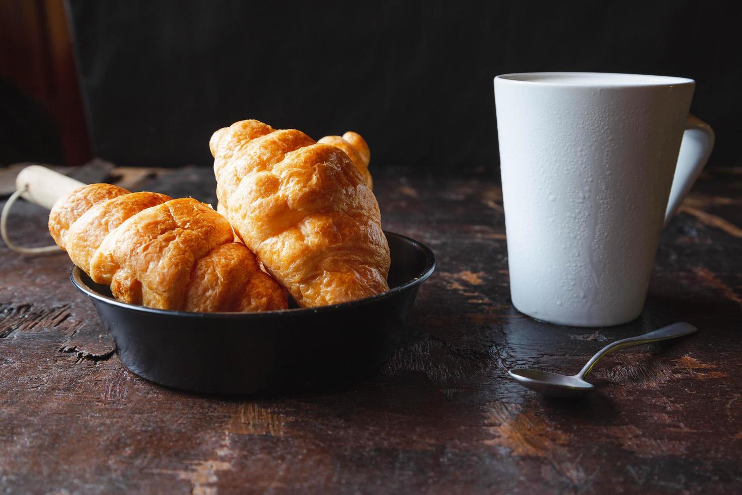 Frühstücksbrot, Croissants und frische Milch auf dem Holztisch. foto