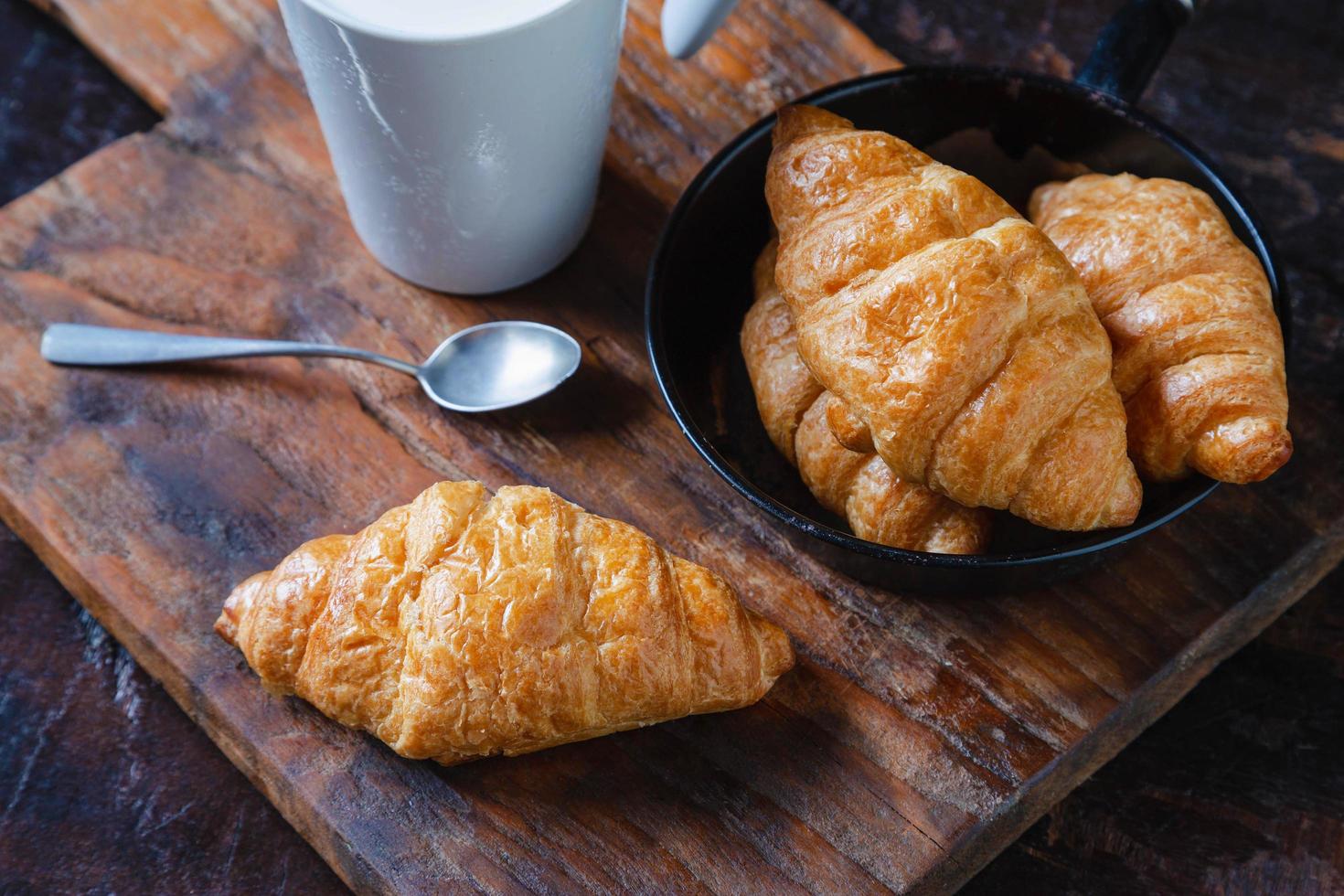 Frühstücksbrot, Croissants und frische Milch auf dem Holztisch. foto