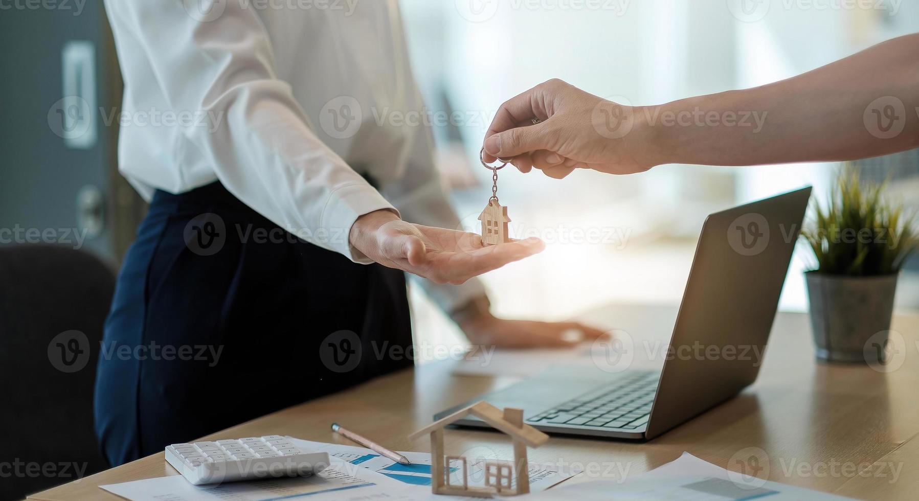 Immobilienmakler, der nach Unterzeichnung der Vertragsvereinbarung im Büro Hausschlüssel für seinen Kunden hält, Konzept für Immobilien, Umzug oder Vermietung von Immobilien foto