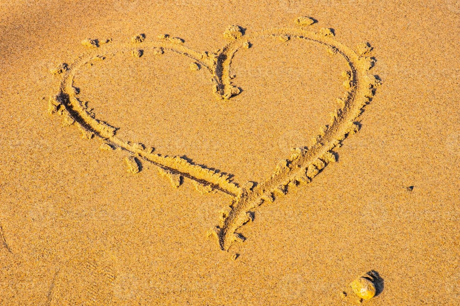 Herz in den Sand gezogen. Strand Hintergrund. Ansicht von oben foto