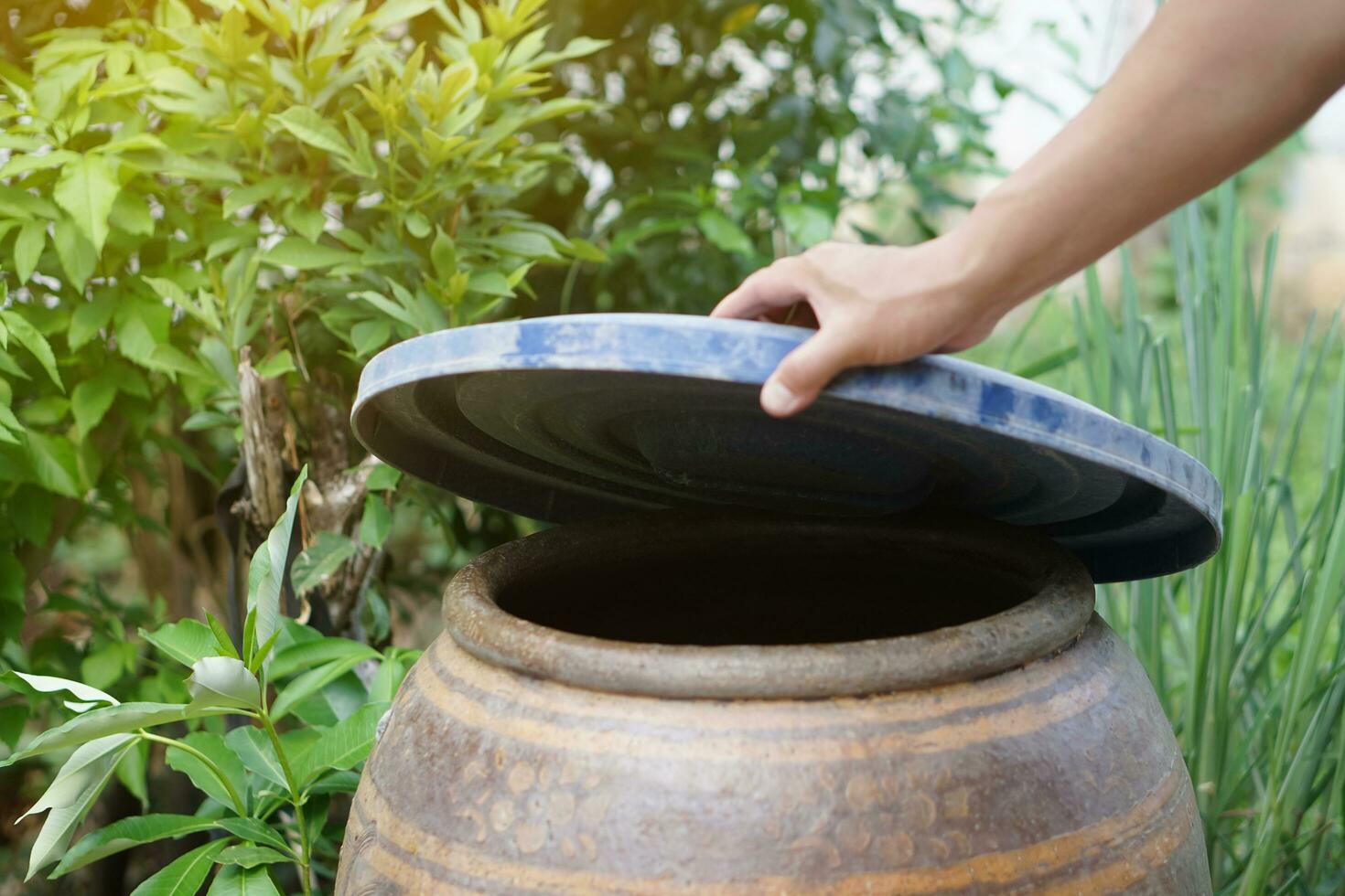 Nahansicht Hand halt Deckel zu Startseite Wasser Eimer zu schützen von Moskito zu Rasse Innerhalb oder andere Insekten oder Staub gehen in Wasser. Konzept, Kampagne zu halt Mücken Zyklus zu legen Eier im Wasser Container foto