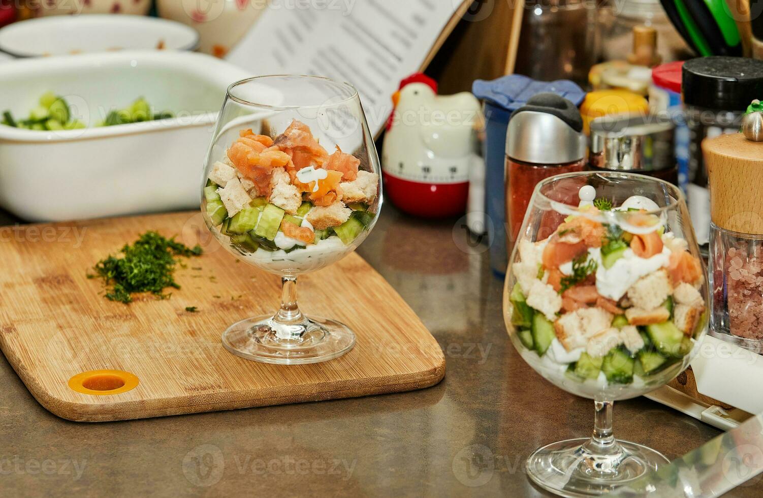 Koch macht Sommer- Salat im Glas von Lachs, Gurken, Croutons, Kräuter und frisch Creme, elegant Sommer- Verschmelzung foto