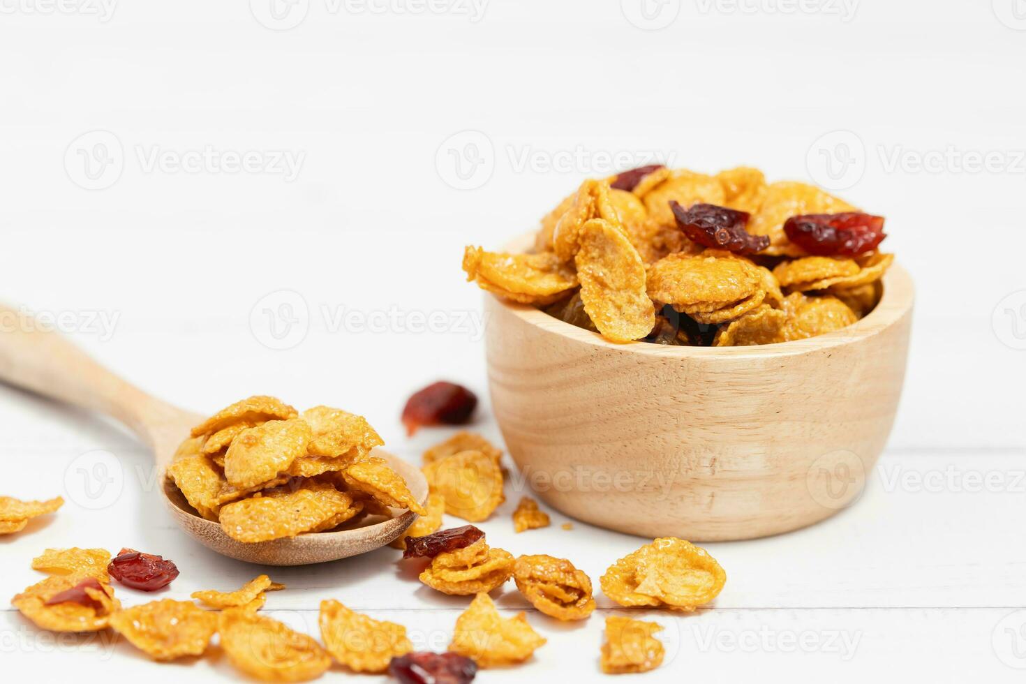 das hölzern Schüssel von Karamell Cornflakes mit Rosinen auf Weiß Hintergrund foto