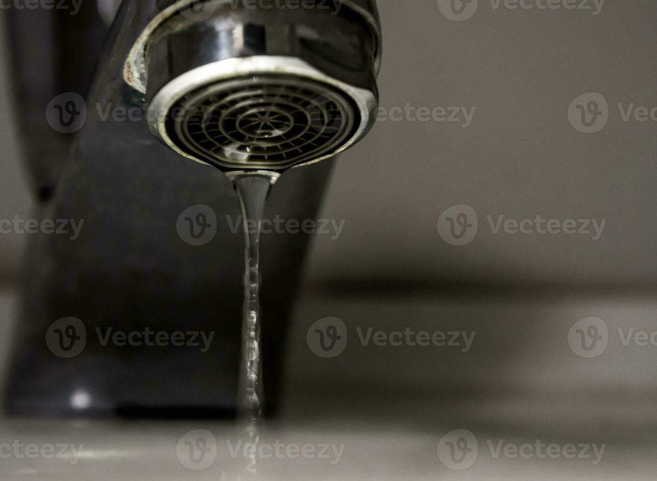 Auslaufende Wassertropfen von altem Rost und fleckigem Wasserhahn foto