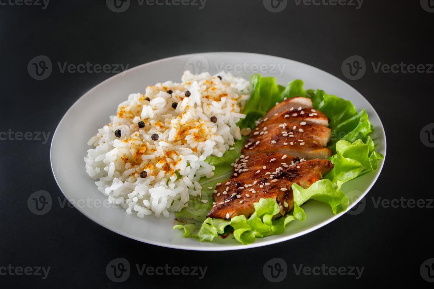 hausgemachtes Essen - Teriyaki-Hühnchen mit weißem Reis und Pfeffer auf schwarzem Hintergrund. foto