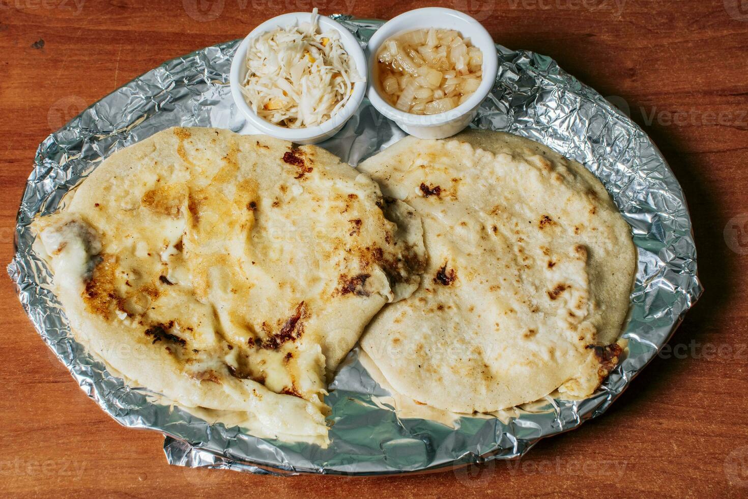 oben Aussicht von zwei nicaraguanisch pupusas serviert mit Salat auf das Tisch. köstlich salvadoran pupusas mit geschmolzen Käse serviert auf das Tisch. traditionell pupusas serviert mit Salat auf das Tabelle foto