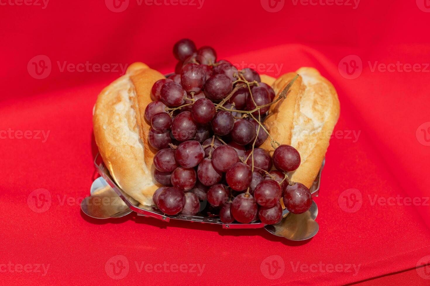 Elemente von das zuletzt Abendessen von Jesus brot, Trauben und Wein auf ein rot Stoff mit hart Beleuchtung foto