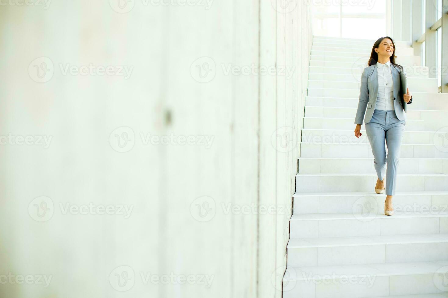 jung Geschäft Frau Gehen Nieder das Treppe und halten Laptop foto