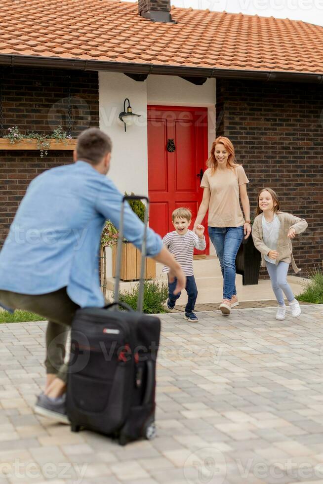 Vater kam Zuhause von das Ausflug und Sohn, Tochter und Ehefrau Laufen zu Treffen ihm foto