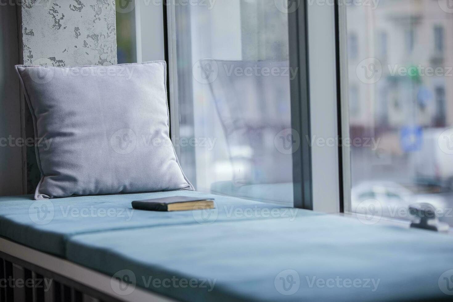 ein Platz zu entspannen beim arbeiten. auf das Fensterbrett Dort ist ein Matratze, ein Kissen und ein Buch. foto
