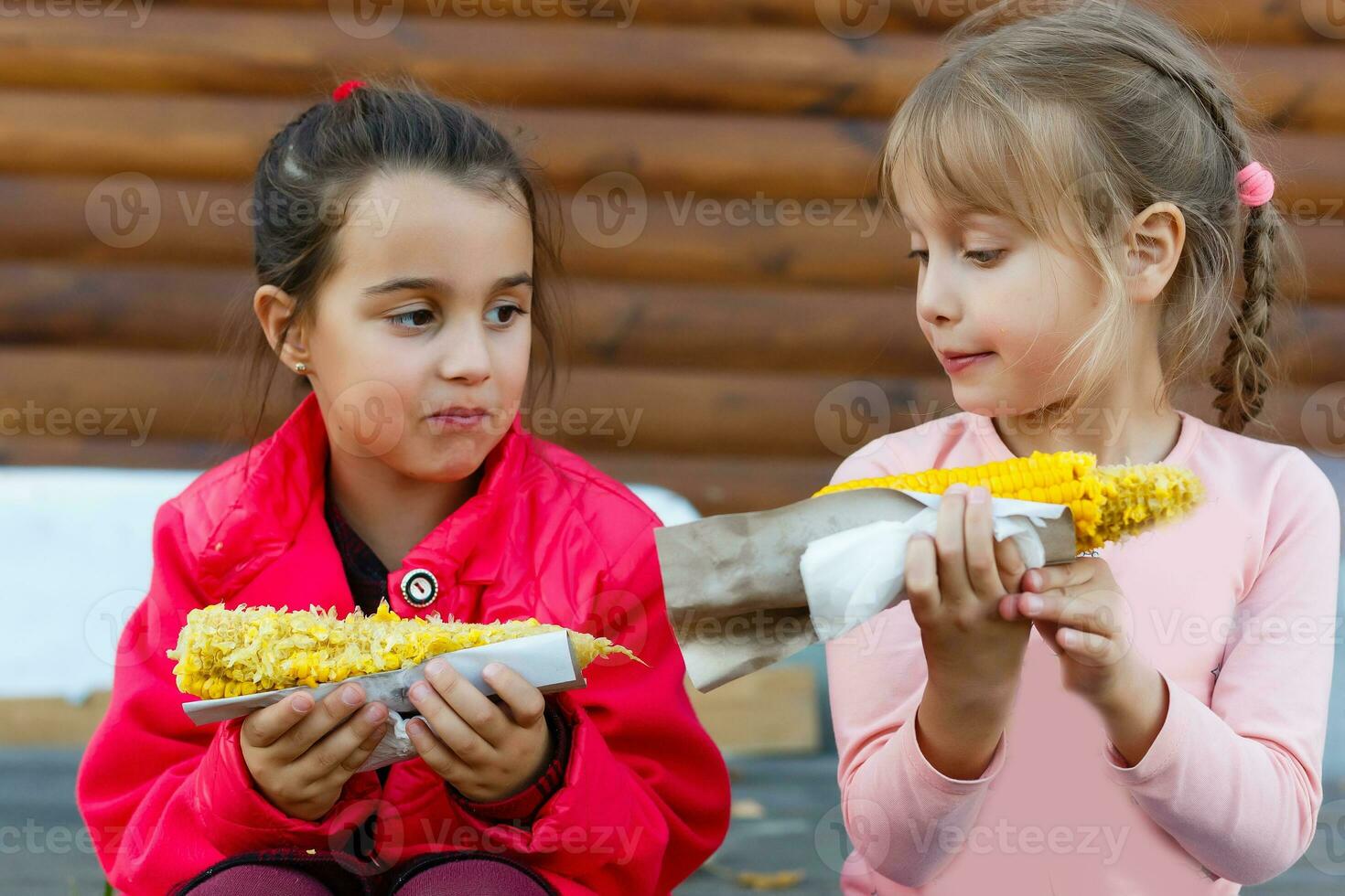 zwei wenig Mädchen Ernte und Essen Mais im Mais Feld. Landwirtschaft Konzept. foto