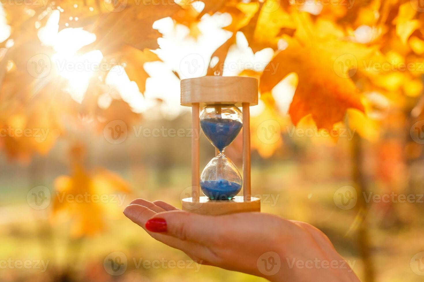 Herbst Zeit Thema, Sanduhr auf gefallen Blätter im verschiedene Farben mit Kopieren Raum. foto