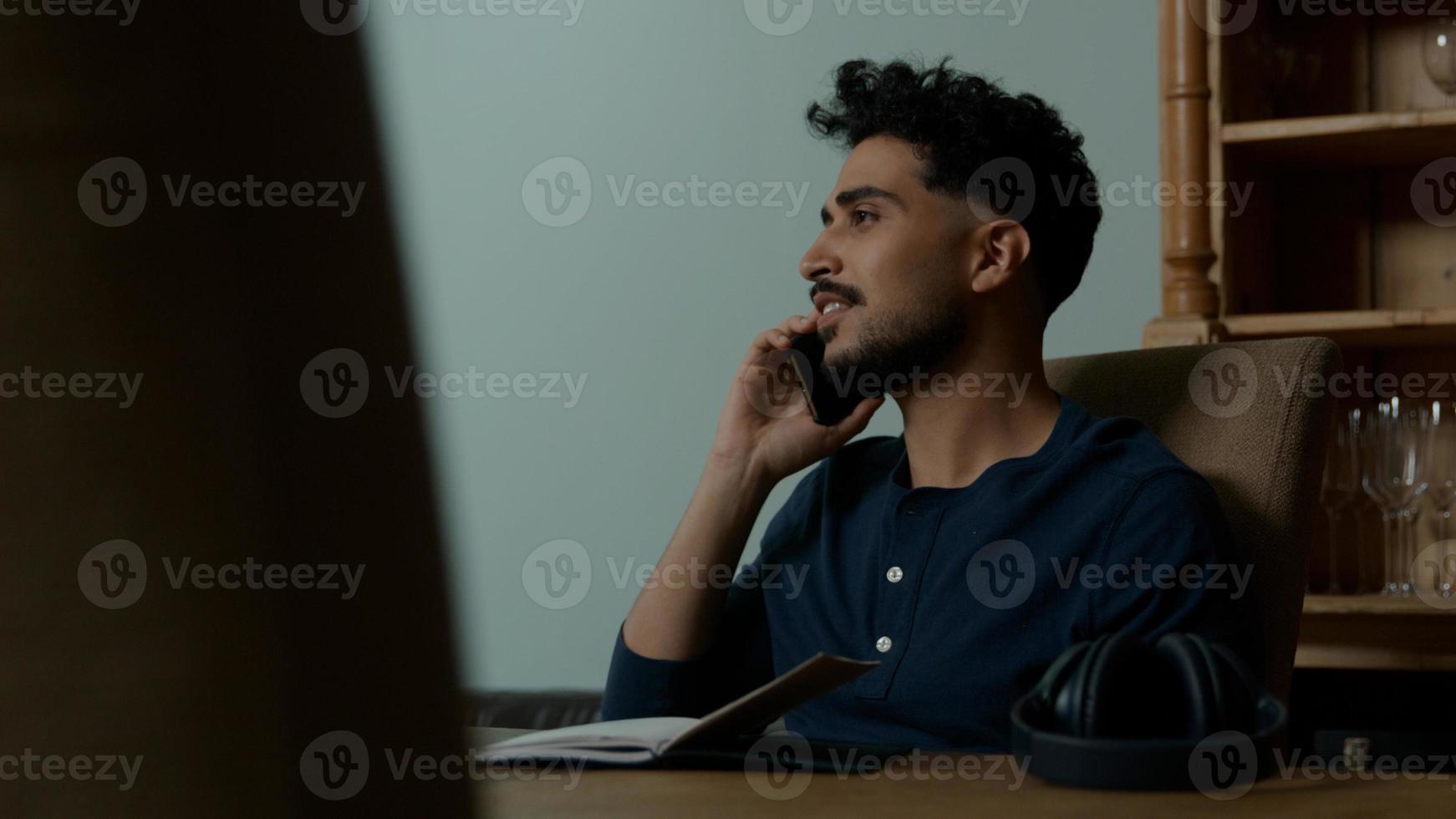 junger Mann am Telefon, der von zu Hause aus arbeitet foto