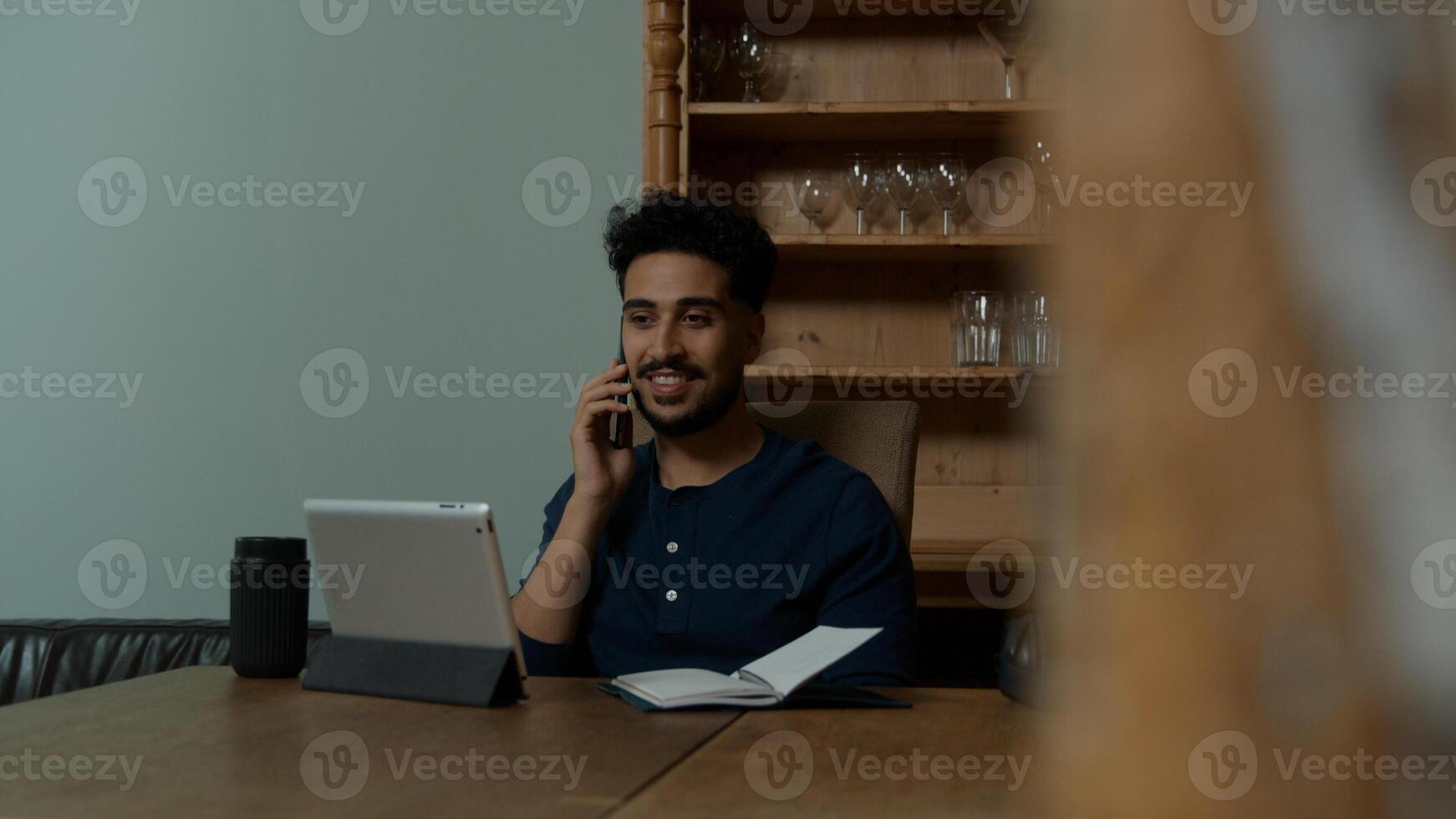 junger Mann am Telefon, der von zu Hause aus arbeitet foto