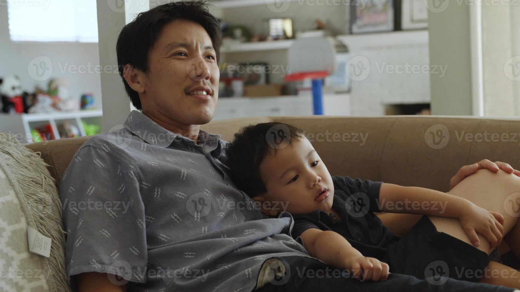 Vater kuschelt kleinen Sohn auf der Couch zu Hause foto