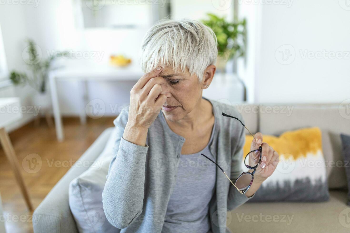 Senior Frau im Brille reibt ihr Augen, Leiden von müde Augen, Okular Krankheiten Konzept foto