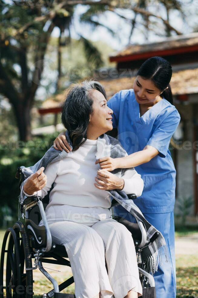 junge asiatische physiotherapeutin, die mit einer älteren frau beim gehen mit einer gehhilfe arbeitet foto