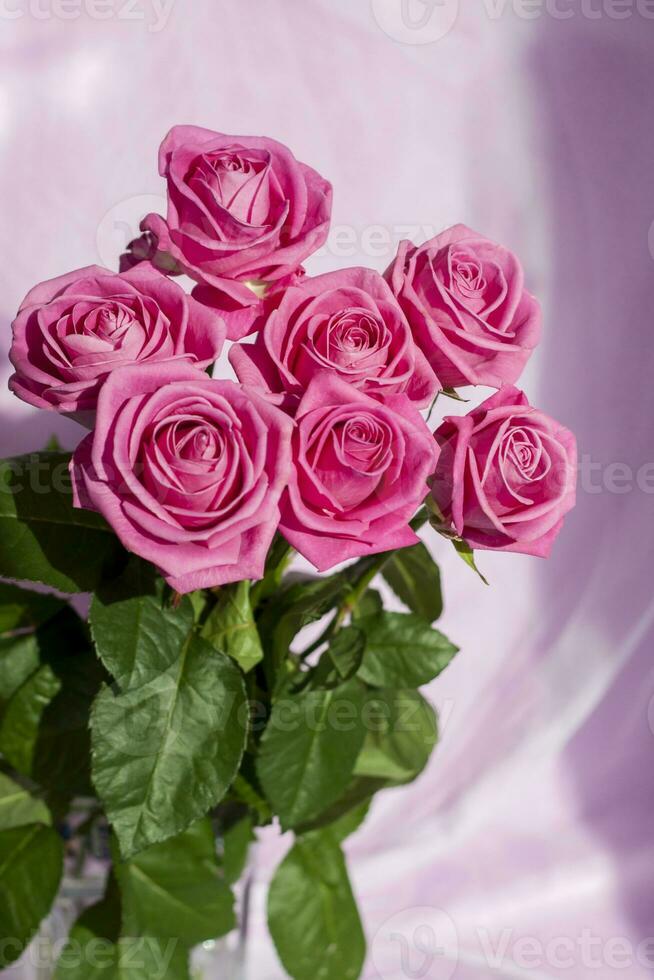 Komposition mit einem Strauß rosa Rosen auf einem zarten Stoffhintergrund. ein Weihnachtsgeschenk, Pastellfarben. festlicher zarter hintergrund, geburtstag, hochzeitsstrauß. valentinstag grußkarte foto