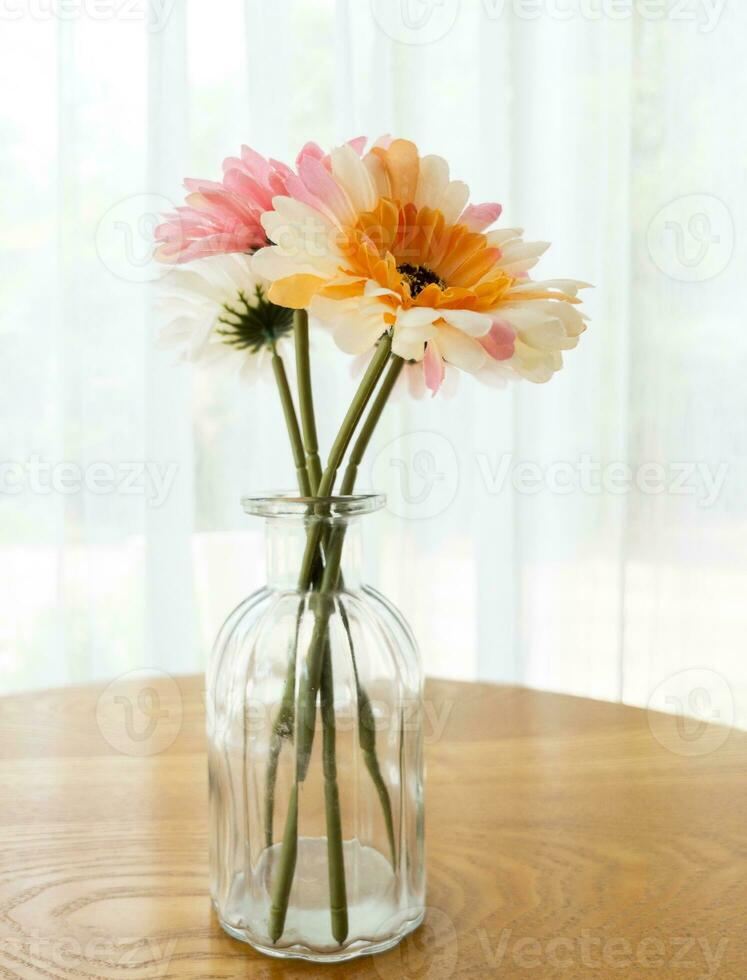 das künstlich Blume im das klar Glas Vase auf das hölzern Tisch. foto