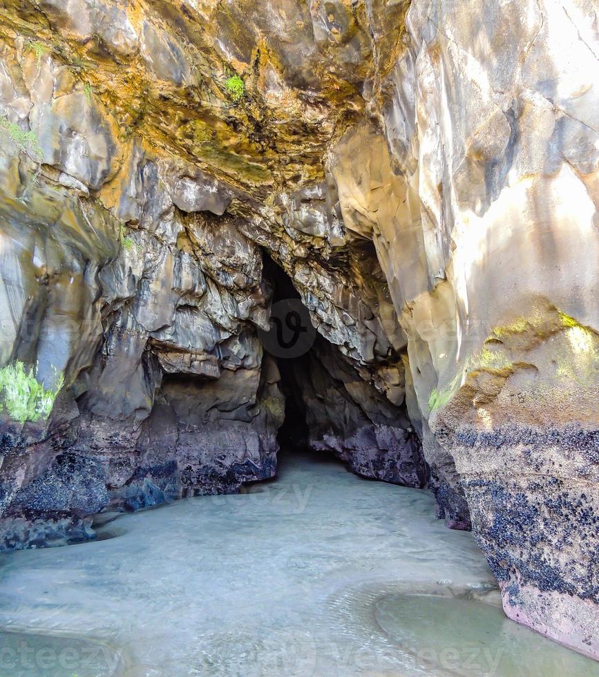 Wasser rollt in eine Höhle am Strand von Muriwai, Auckland, Neuseeland foto