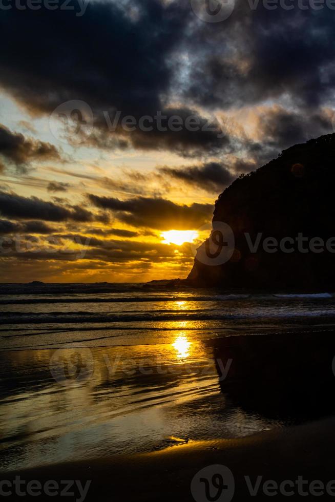 Sonnenuntergang und Wellen am Strand. bethels beach, auckland, neuseeland foto