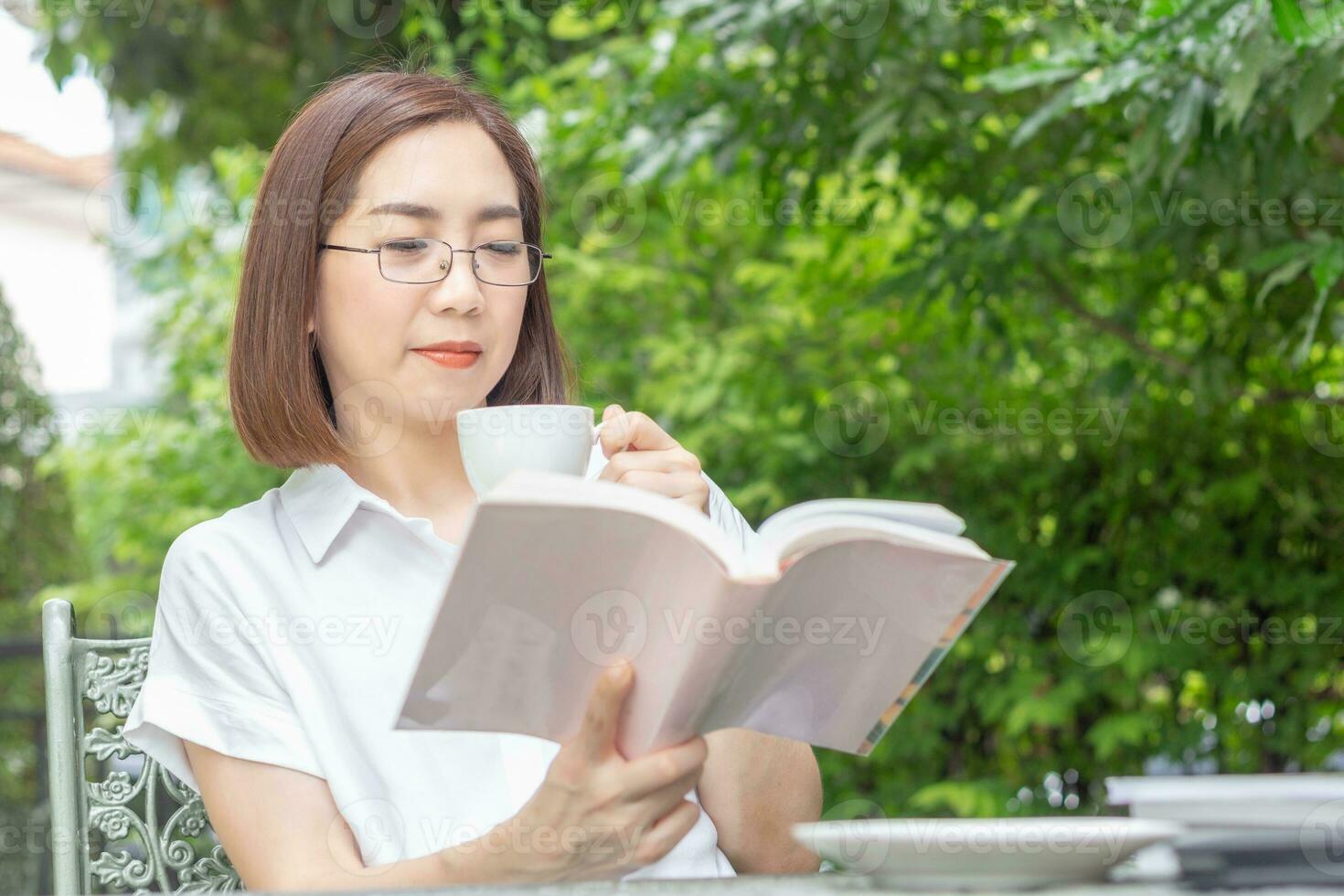 asiatisch Mitte alt Frau im Brille lesen ein Buch im Hinterhof foto