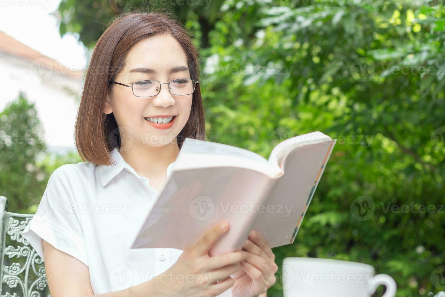 asiatisch Mitte alt Frau im Brille lesen ein Buch im Hinterhof foto