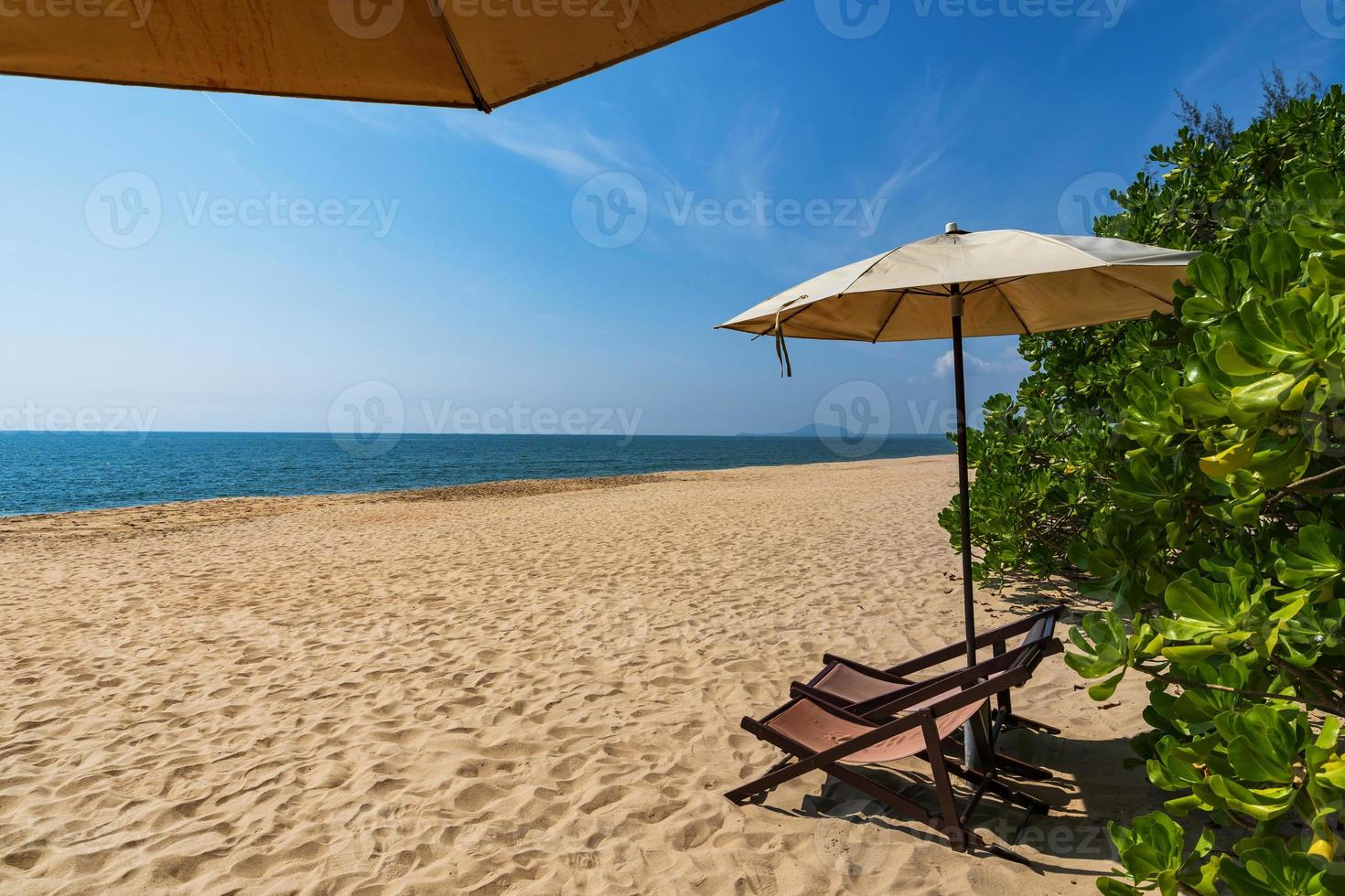 tropischer Strand mit Sonnenschirm unter Palmen im Sonnenlicht, Urlaubshintergrund foto