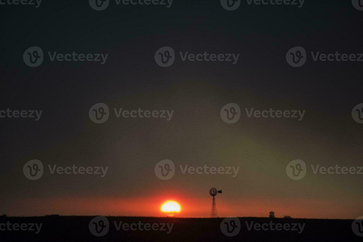 ein Windmühle ist silhouettiert gegen ein dunkel Himmel foto