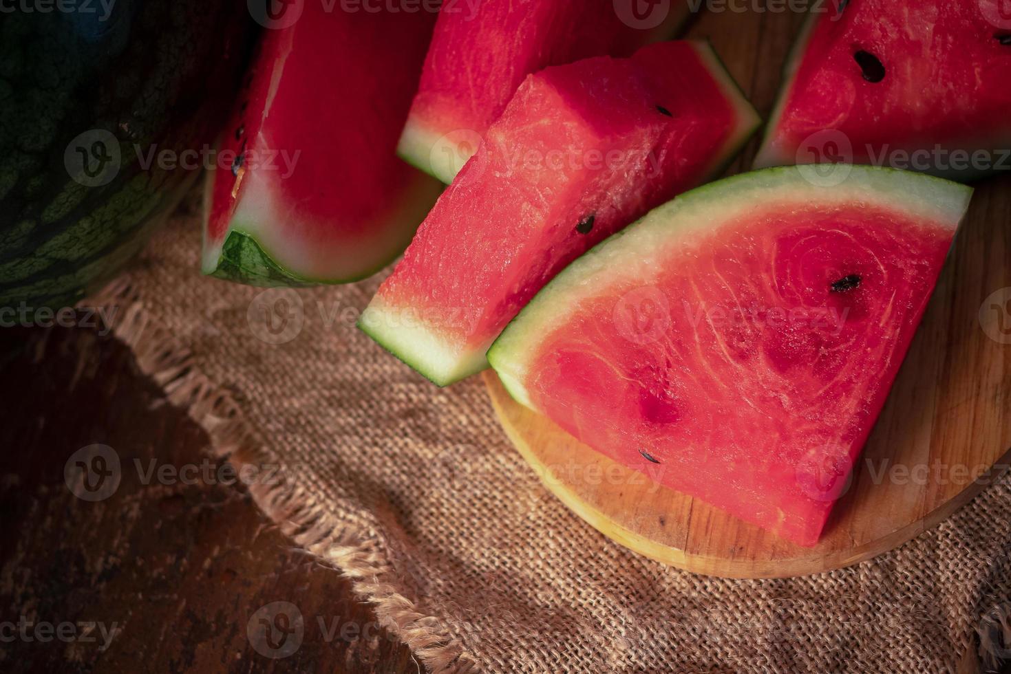 Wassermelone und Wassermelonenstücke in einem Holzhintergrund foto
