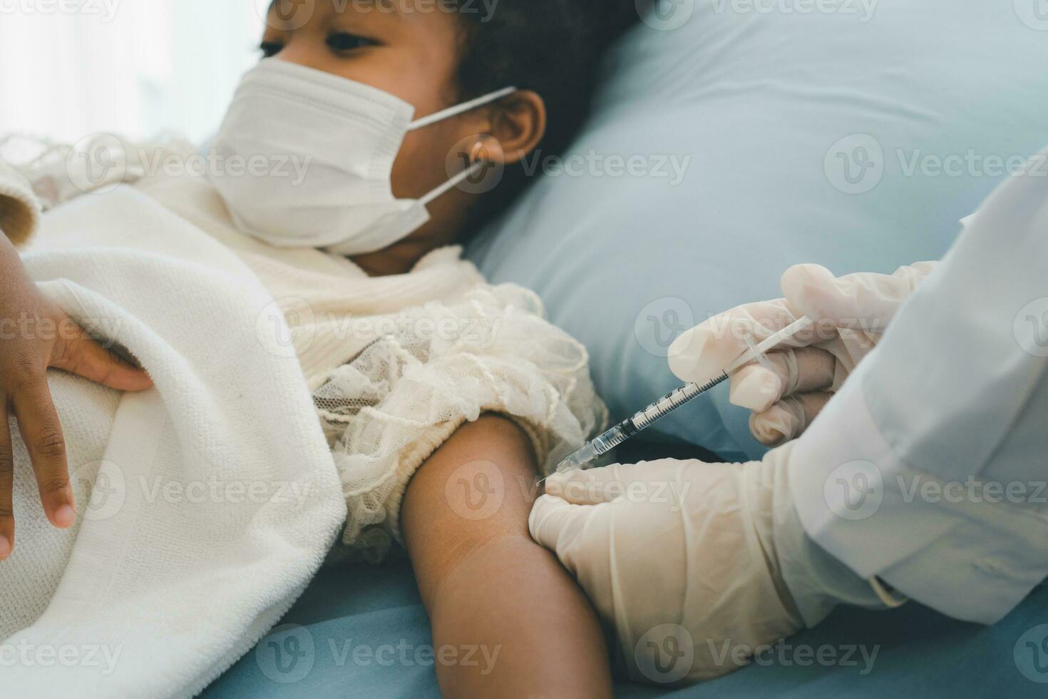 asiatisch Arzt Benutzer Spritze Nadel zum Injektion impfen, afrikanisch amerikanisch Kinder sind Sein covid geimpft zum Verhütung Coronavirus und Grippe. Konzept von Immunisierung von Impfung foto