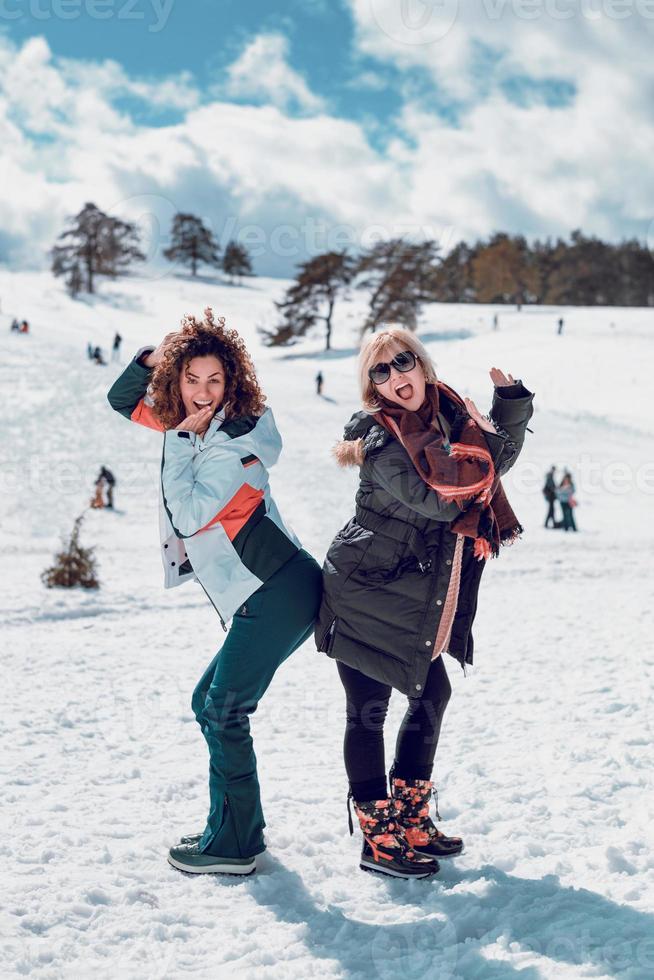 Zwei glückliche Frauen, die am sonnigen Wintertag im Schnee stehen und Spaß haben. foto
