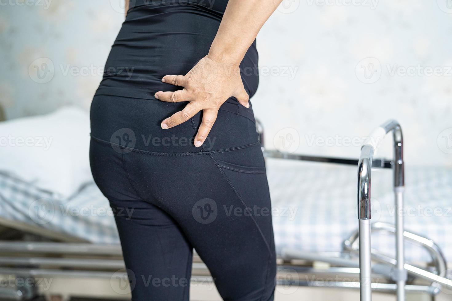 asiatische Patientin mit Rückenschmerzen-Unterstützungsgurt für orthopädische Lendenwirbelsäule mit Gehhilfe. foto
