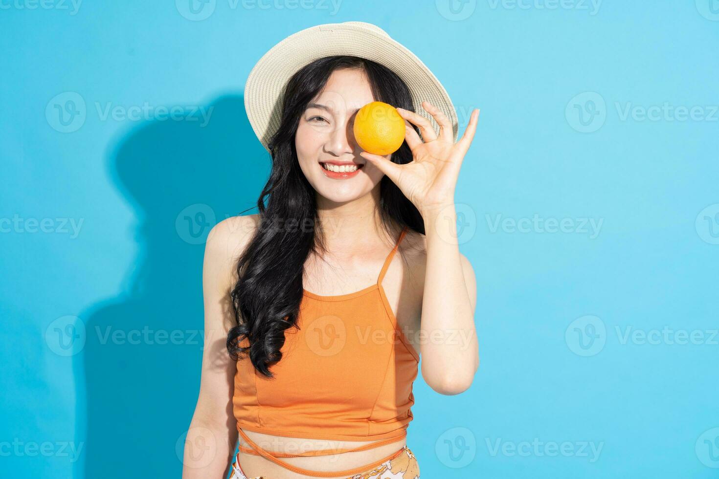 Porträt von ein schön asiatisch Mädchen im ein Badeanzug lächelnd glücklich auf ein Blau Hintergrund foto
