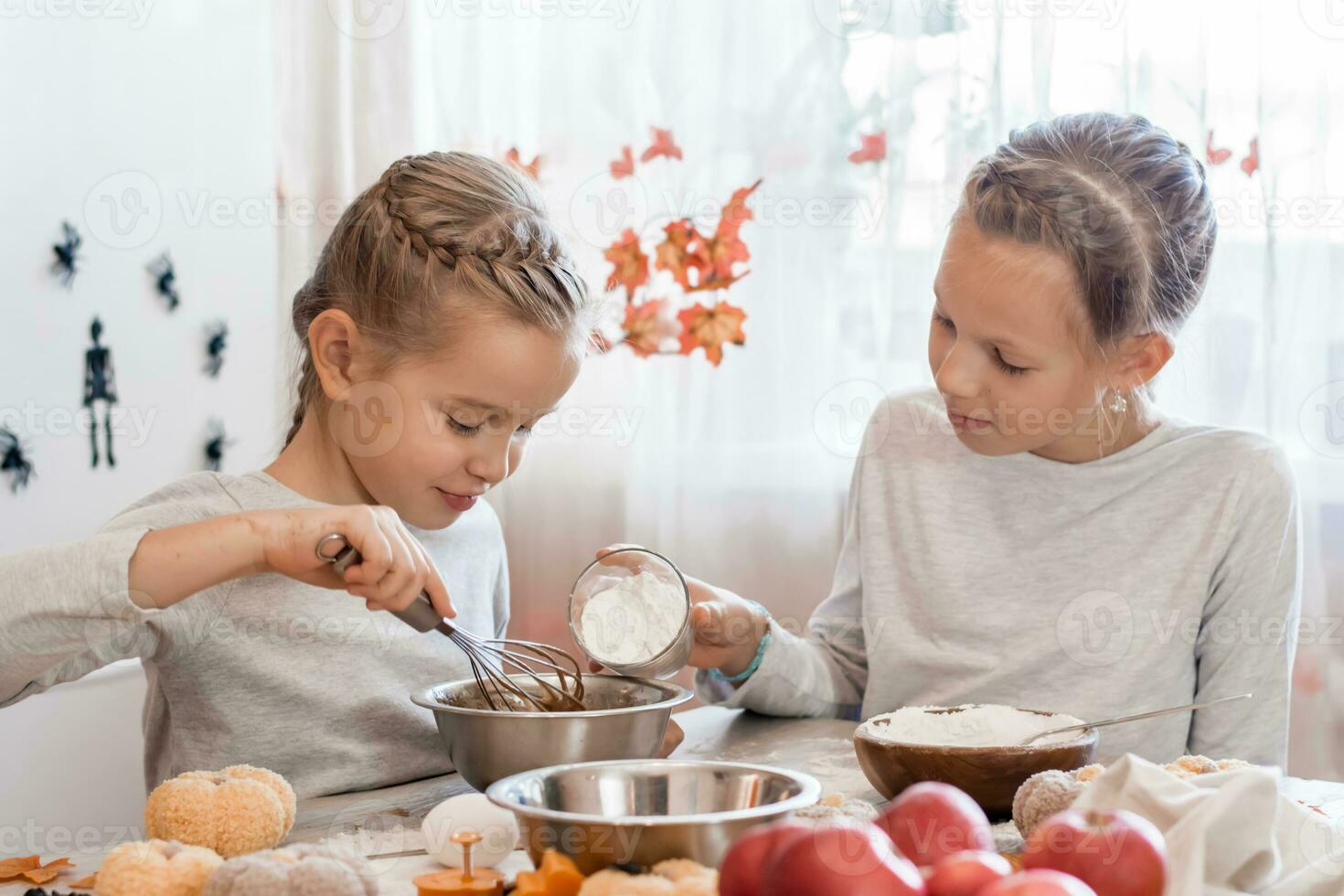 Leckereien und Vorbereitungen zum das Feier von Halloween. süß wenig Mädchen fügt hinzu Mehl zu Backen Plätzchen Teig zum Halloween im das Küche. foto