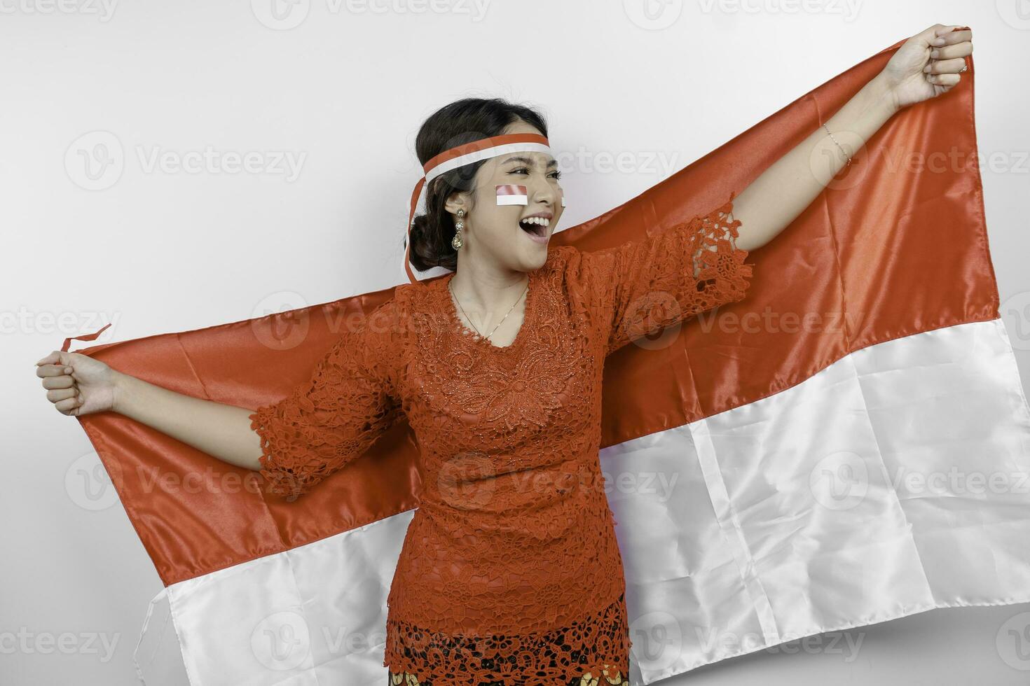 glücklich lächelnd indonesisch Frau tragen rot Kebaya und Stirnband halten Indonesiens Flagge zu feiern Indonesien Unabhängigkeit Tag isoliert Über Weiß Hintergrund. foto