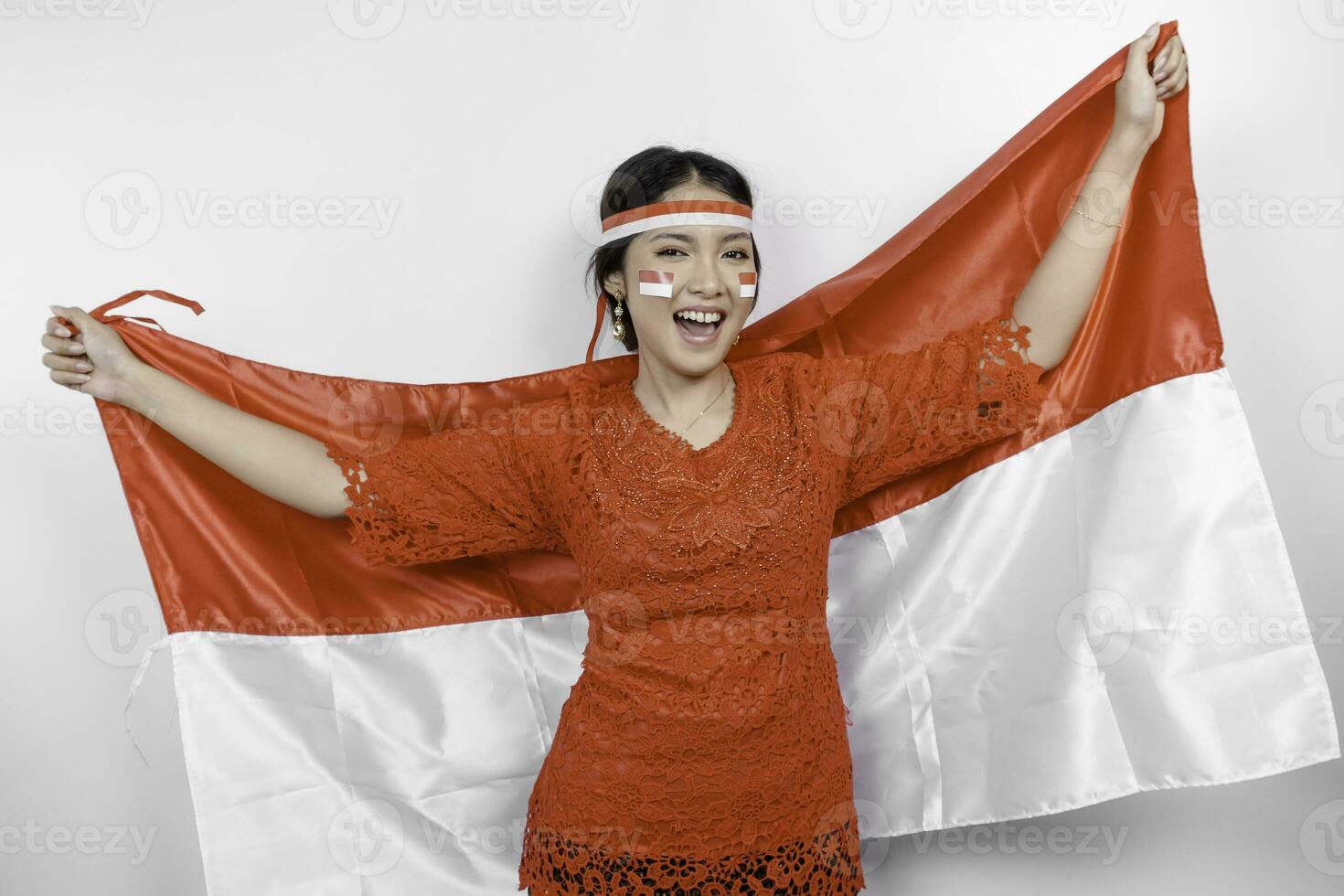 glücklich lächelnd indonesisch Frau tragen rot Kebaya und Stirnband halten Indonesiens Flagge zu feiern Indonesien Unabhängigkeit Tag isoliert Über Weiß Hintergrund. foto