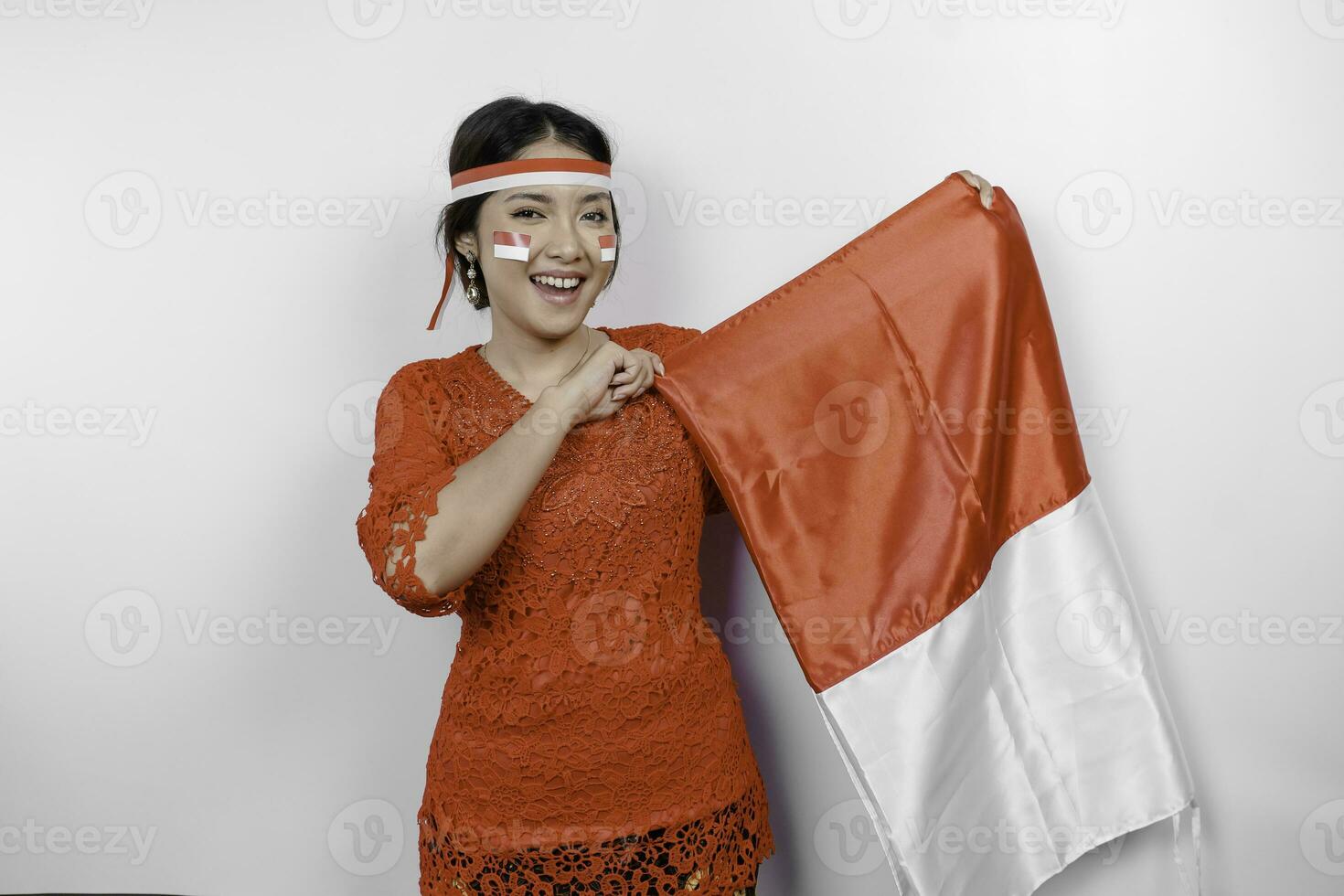 glücklich lächelnd indonesisch Frau tragen rot Kebaya und Stirnband halten Indonesiens Flagge zu feiern Indonesien Unabhängigkeit Tag isoliert Über Weiß Hintergrund. foto