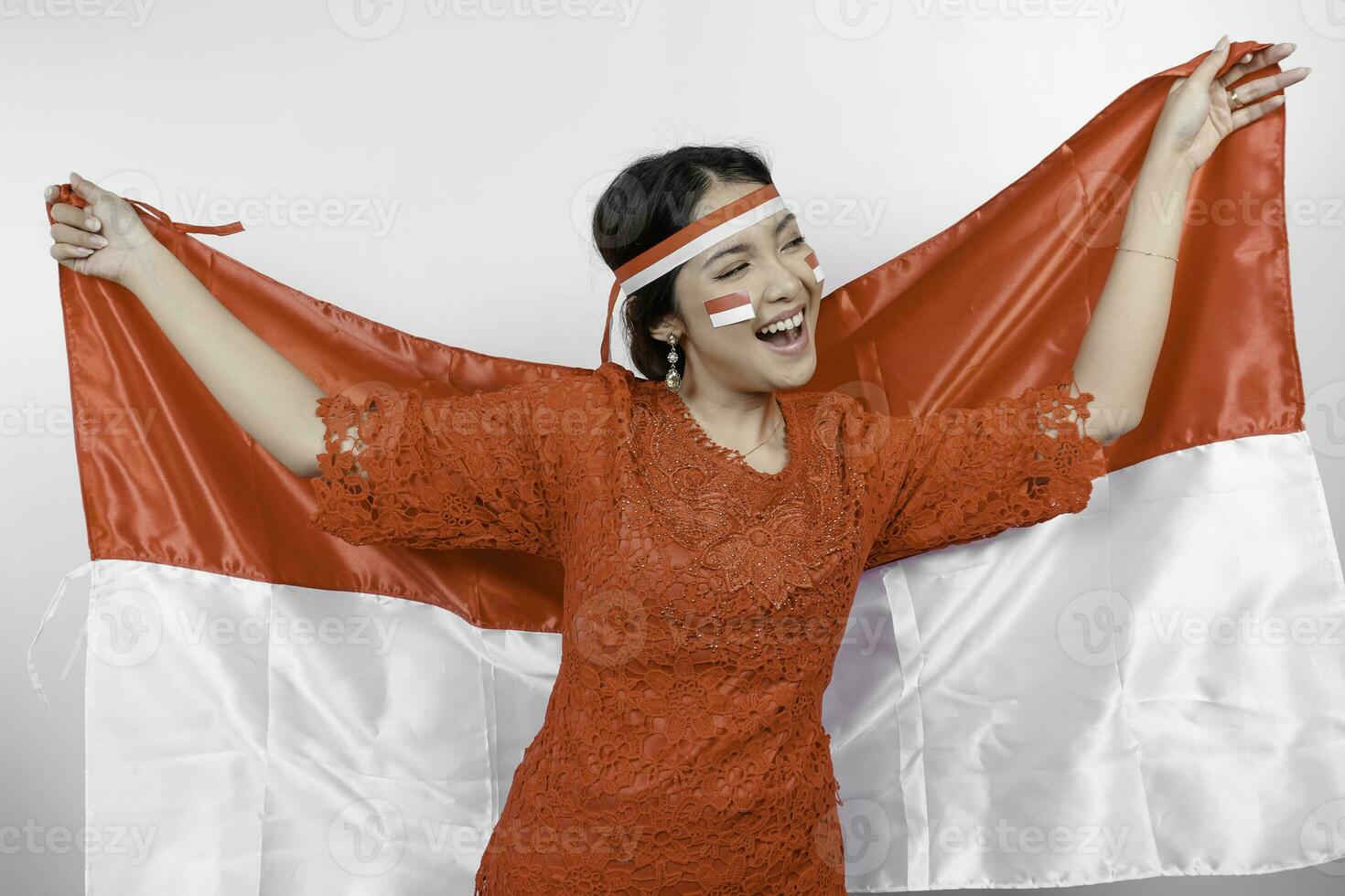 glücklich lächelnd indonesisch Frau tragen rot Kebaya und Stirnband halten Indonesiens Flagge zu feiern Indonesien Unabhängigkeit Tag isoliert Über Weiß Hintergrund. foto