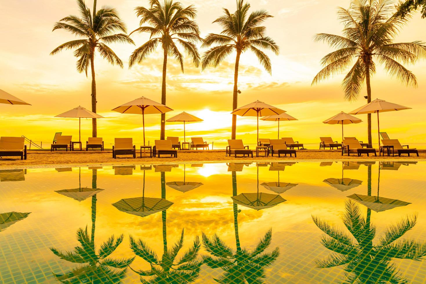 Sonnenschirm und Stuhl um den Pool im Hotelresort mit Sonnenaufgang am Morgen? foto