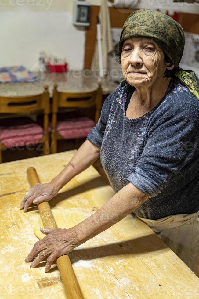 Oma rollt den frisch gekneteten Teig aus foto