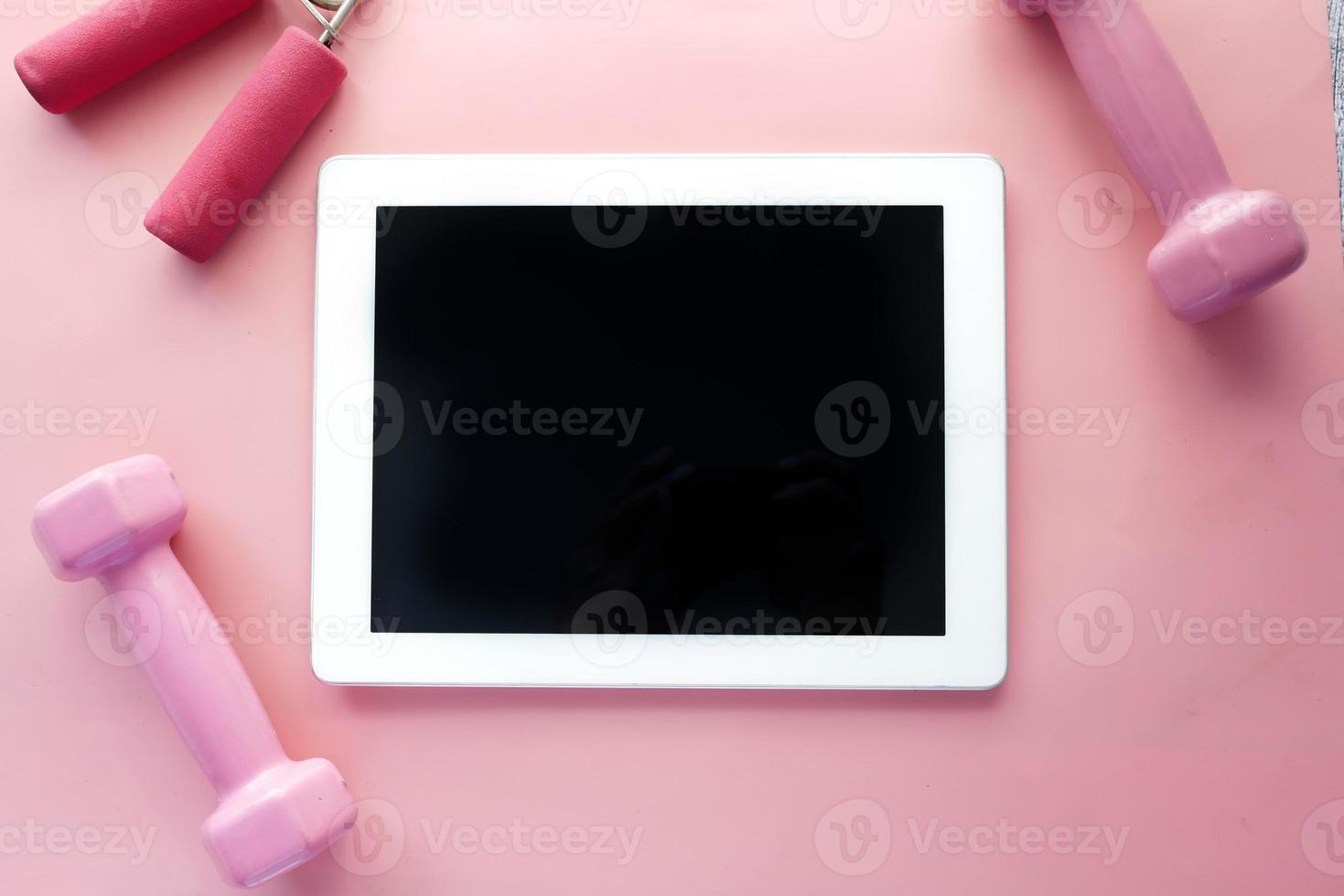 digitales Tablet mit Sportgeräten auf rosa Hintergrund foto