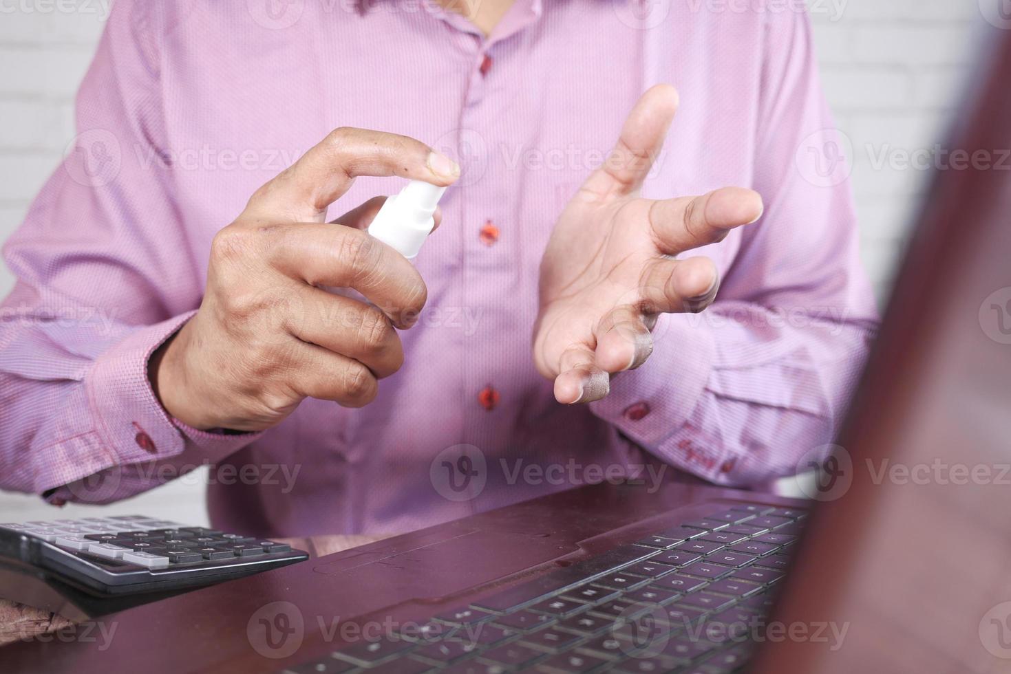 Nahaufnahme der Hand des jungen Mannes mit Handdesinfektionsspray. foto