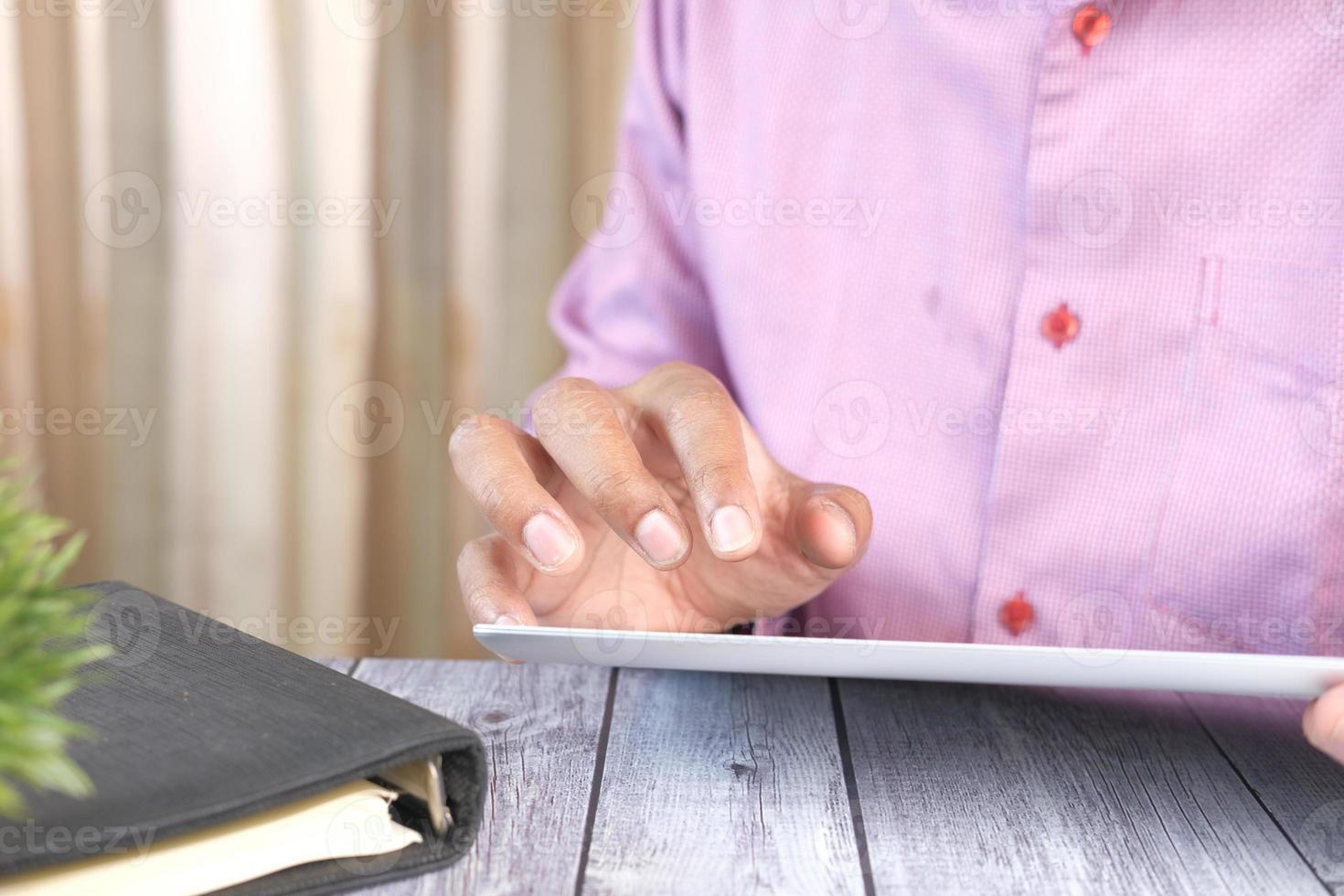 Geschäftsmann, der digitales Tablett auf Schreibtisch verwendet foto