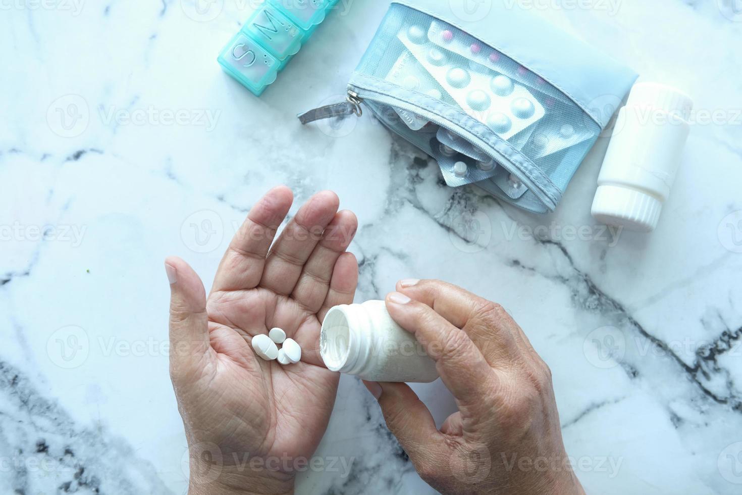 Hand des älteren Mannes mit Medizin, die aus der Draufsicht des Pillenbehälters verschüttet wurde foto