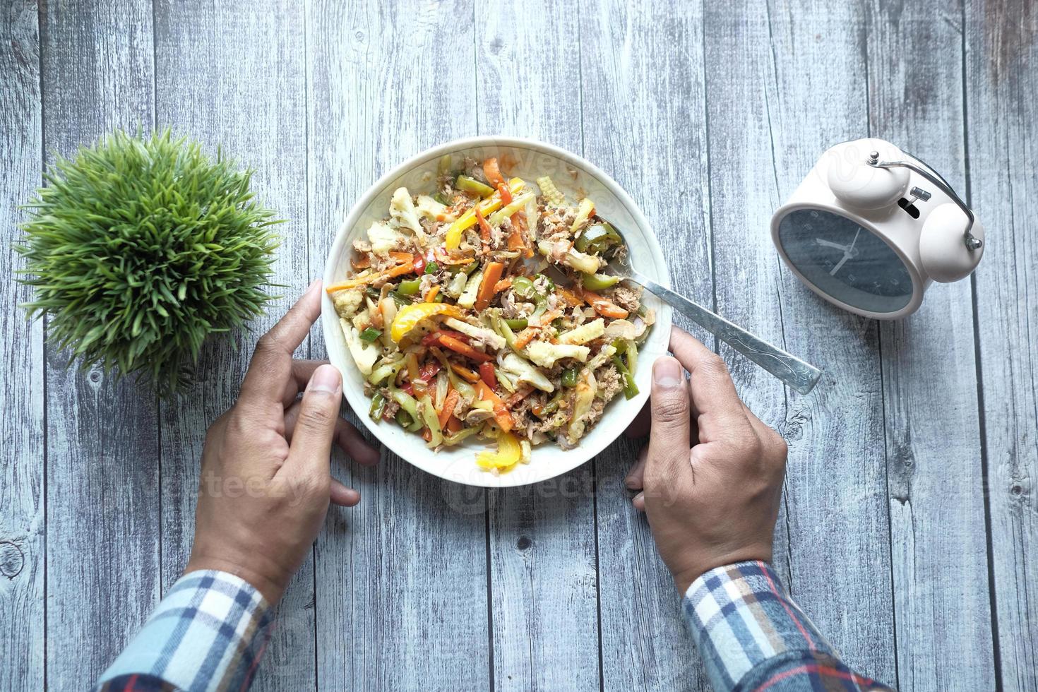 junger Mann in Freizeitkleidung, der frischen Salat isst, gesundes Lebensmittelkonzept foto