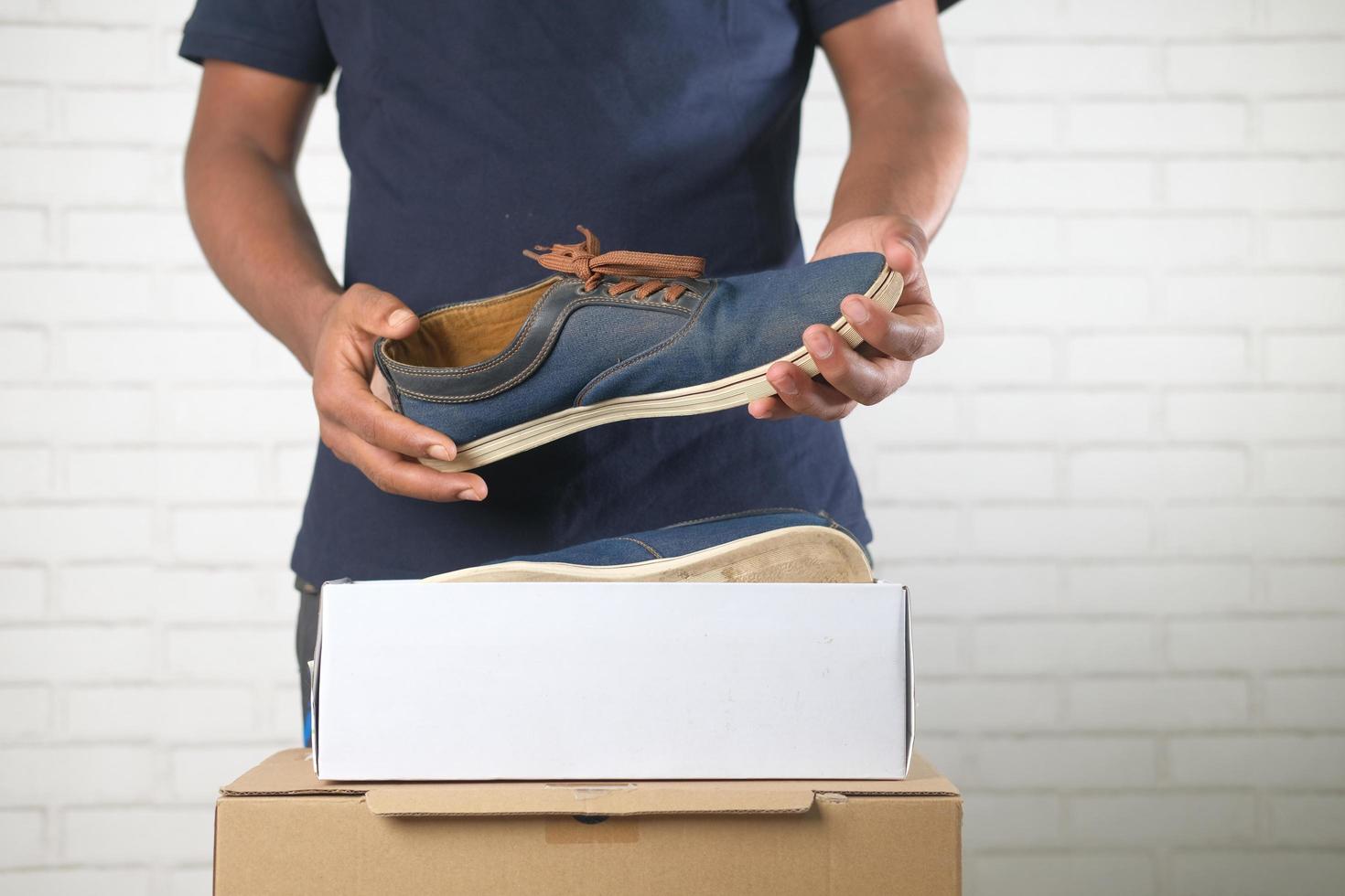 junger Mann öffnet eine Kiste für Schuhe foto