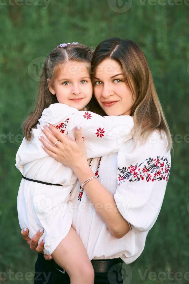 kaukasisch bezaubernd wenig Mädchen kuscheln ihr Mutter. ukrainisch National Kleidung, Stickerei, Traditionen foto